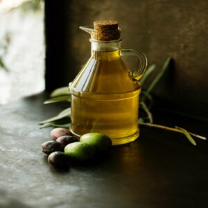 jarre d'huile d'olive sur une table avec olives à côté