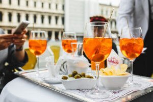 plateau avec plusieurs verres de spritz en terrasse et coupelles de chips et olives