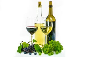 Bouteilles et verre de vin blanc avec grappes de raison autour dans un fond blanc